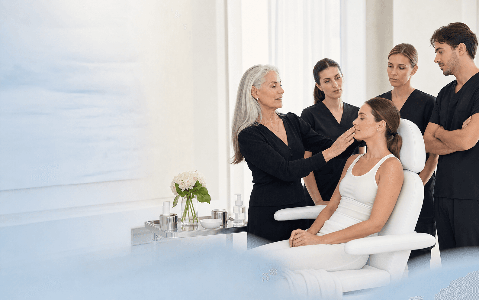 Aesthetic medicine educator consulting with a patient alongside clinical trainees